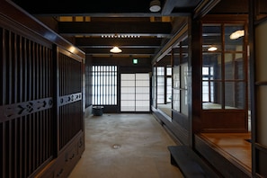 A traditional Japanese room with tatami flooring, sliding doors, and a low wooden bench.