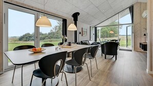 Un comedor moderno con una mesa larga, sillas negras y lámparas colgantes.