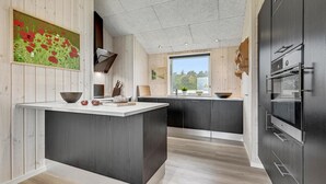 Una cocina moderna con una isla central, paredes de madera y un amplio ventanal con vistas al exterior.