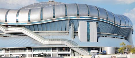 A modern stadium with a curved roof, multiple levels, and a prominent entrance.