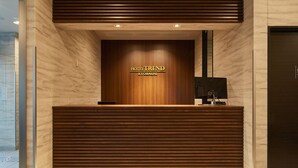 Uma mesa de recepção com acabamento em madeira e uma placa com a inscrição 'HOTEL TREND KYOBASHI'.