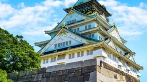 Um castelo japonês tradicional com vários níveis e decoração dourada ornamentada.