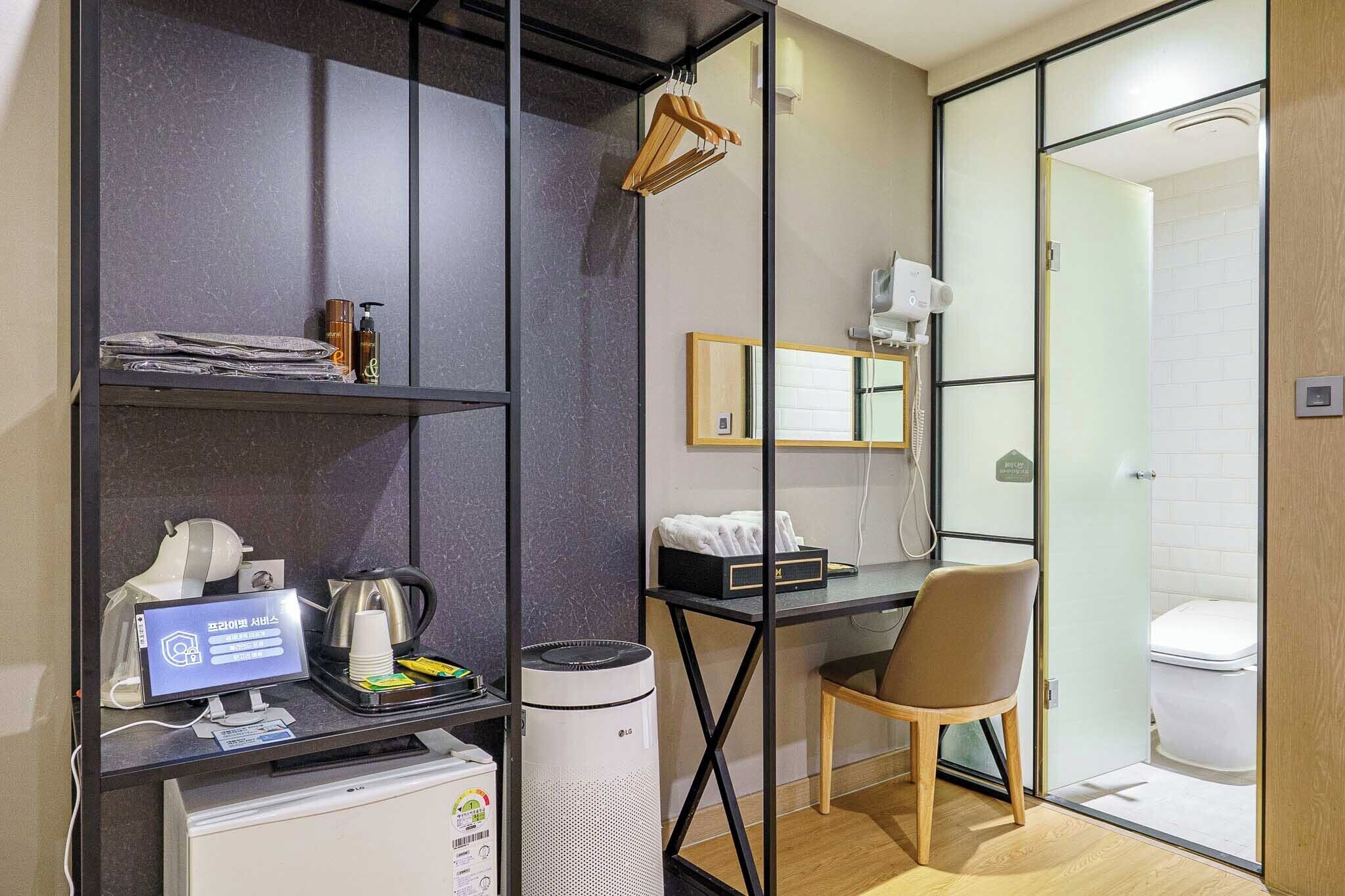 Habitación de hotel moderna con escritorio, silla y zona de ducha.