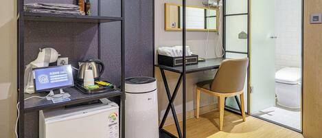 Habitación de hotel moderna con escritorio, silla y zona de ducha.