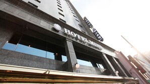 A hotel with a modern facade, large windows, and a prominent sign. - Mind Hotel (Seoul)