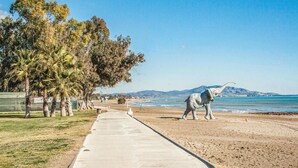Un paseo marítimo con palmeras y una gran estatua de elefante.