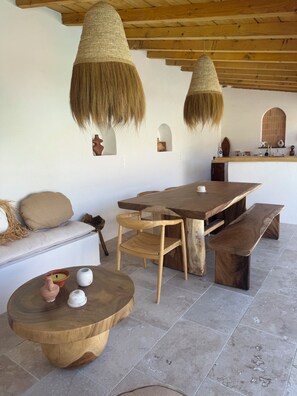 A rustic interior with a wooden dining table, benches, and a round wooden table with decorative items. - Air-conditioned house near Cassis (CARNOUX EN PROVENCE)