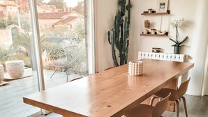 Un comedor con una mesa de madera y cuatro sillas, un cactus y estantes con objetos decorativos.