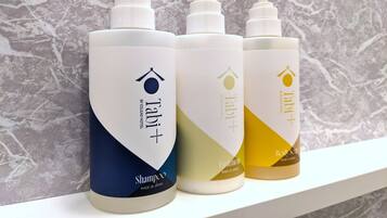 Four bottles of shampoo on a shelf against a marble wall.