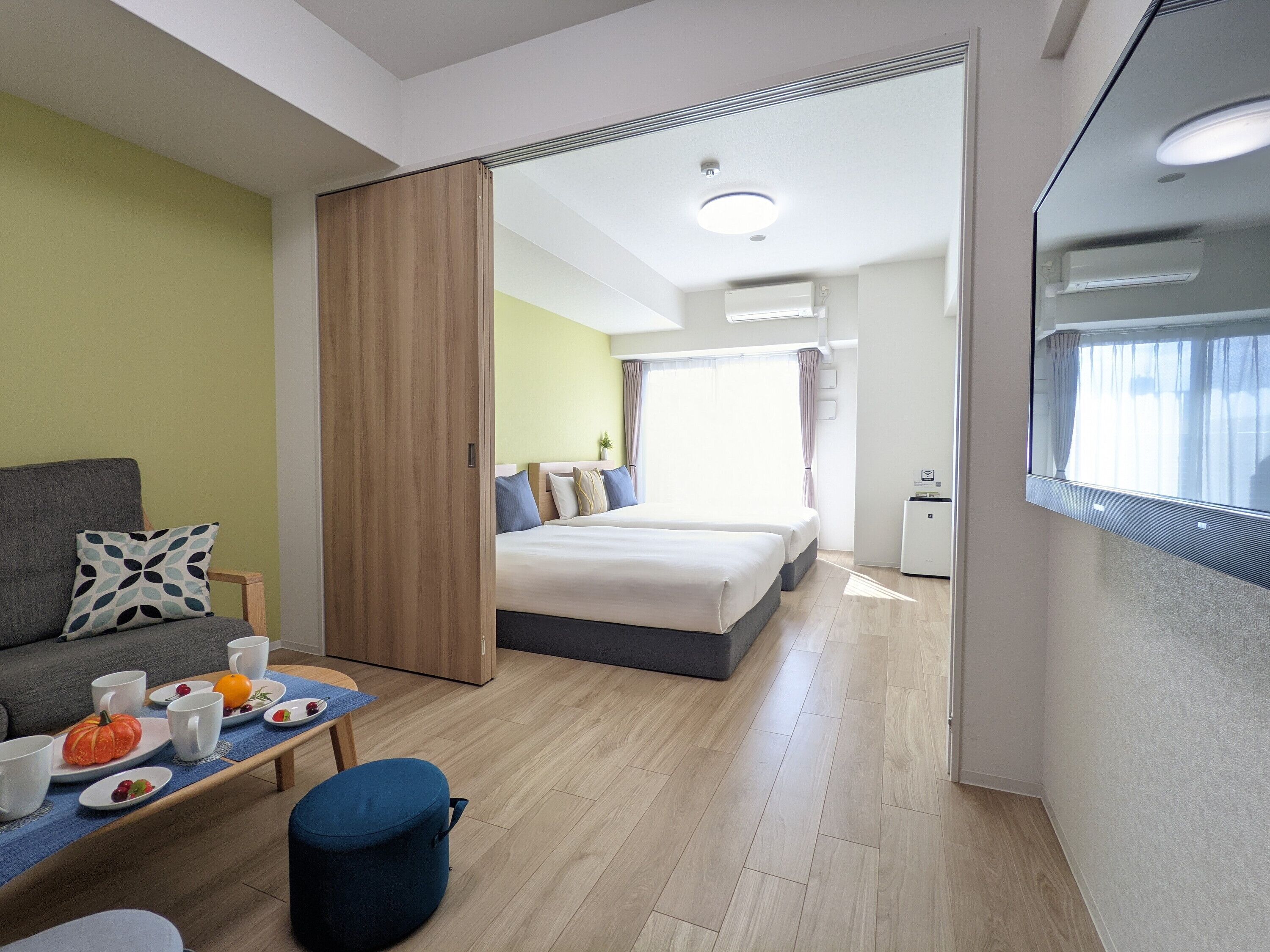 Una habitación de hotel con cama, sofá, mesa de comedor con alimentos para el desayuno y una pequeña cocina.