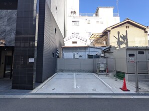 A narrow urban street with a gated entrance, a building with a metal gate, and a red traffic cone. - Eslead Hotel Namba South Ⅲ (Osaka)
