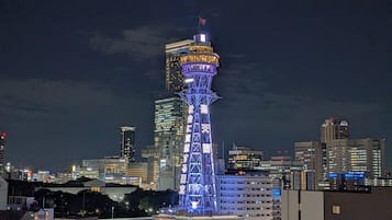 A tall, illuminated tower with a flag at the top, surrounded by a cityscape at night.
