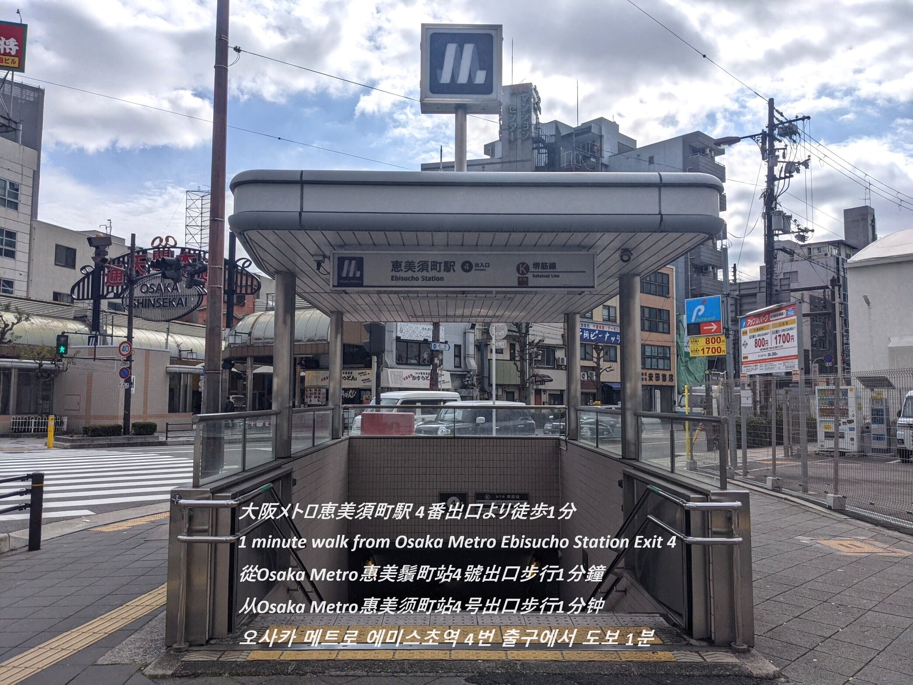 Un passage piéton situé à l’entrée d’une gare, avec un abri et un panneau indiquant la sortie.