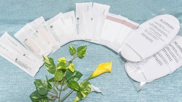 A series of white paper items with text, arranged in a semi-circle on a textured surface, with a green plant and a yellow flower nearby.