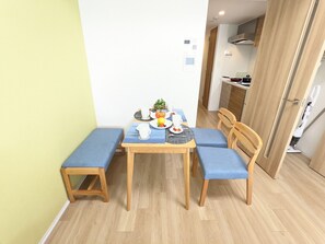 Een eetgedeelte met een houten tafel, blauw gestoffeerde stoelen en een bank.