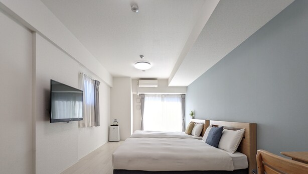 A modern hotel room with a large bed, a flat-screen TV, a heater, and a view of the outdoors.