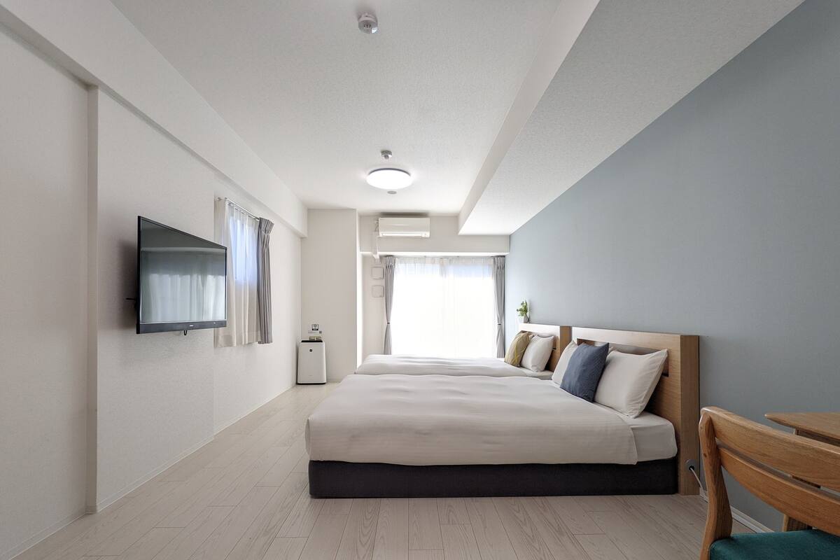 A modern hotel room with a large bed, a flat-screen TV, a heater, and a view of the outdoors.