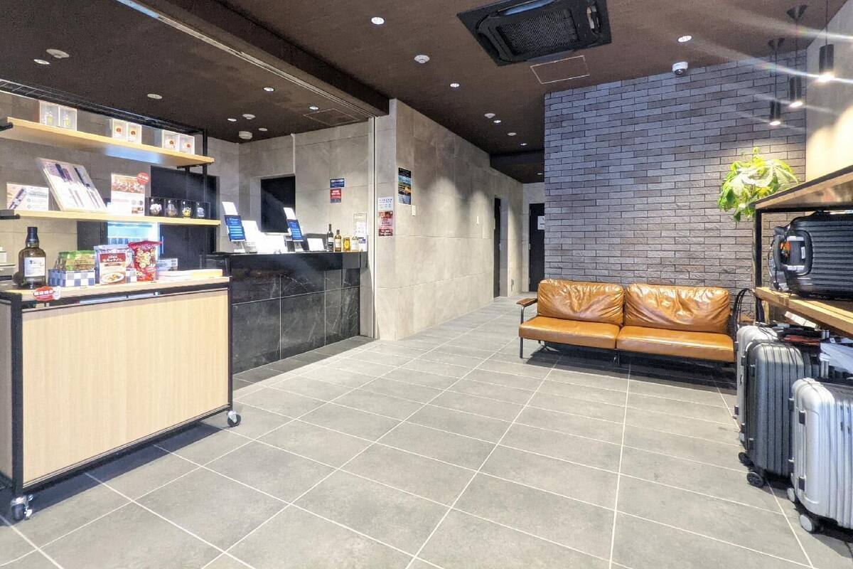 A reception area with a counter, a leather couch, and luggage.
