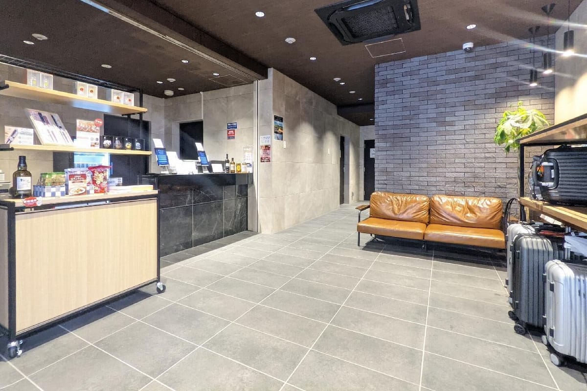 A reception area with a counter, a leather couch, and luggage.