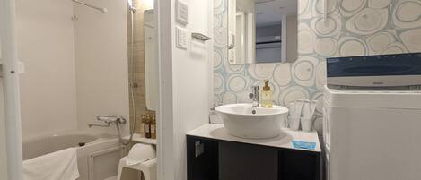 A bathroom with a bathtub, a sink, a mirror, and a towel rack.
