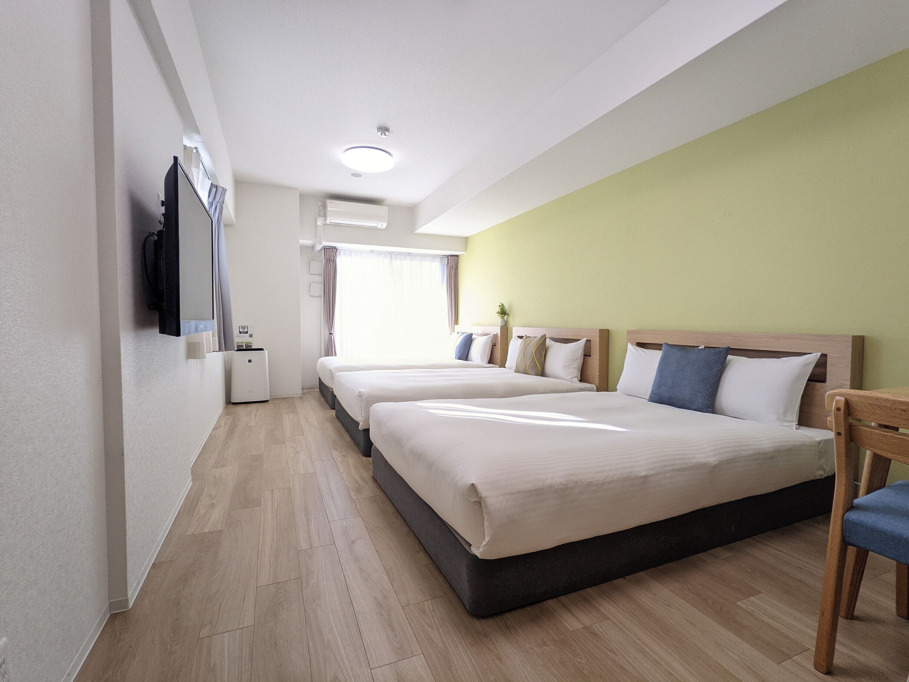 A hotel room with two beds, a desk, a chair, and a television.