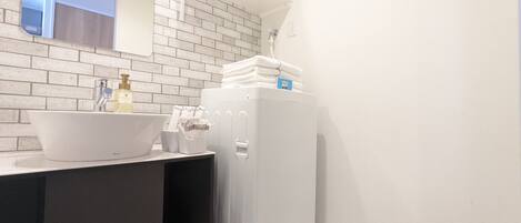 Een badkamer met een wit wastafel, een spiegel, een handdoekrek en een wit toilet.