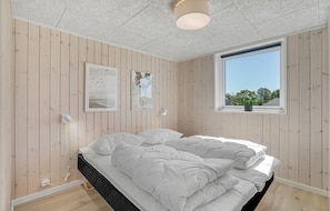 Relax in a serene space with a large bed, framed views, and a natural ambiance.