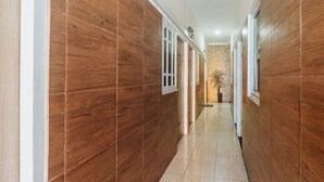 A hallway with wooden paneling and tiled flooring, leading to a door with a window. - OYO 2010 Satria Guest House (Ambon)