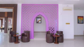 A reception area with a purple decorative partition, two brown leather chairs, and a small table with a vase.