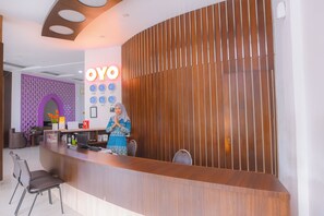 Un comptoir d’accueil avec un panneau décoratif en bois, un panneau indiquant « YOYO » et plusieurs horloges.