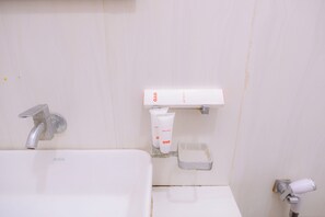 Een badkamer met een wit wastafel, een handdouche en een zeepdispenser.