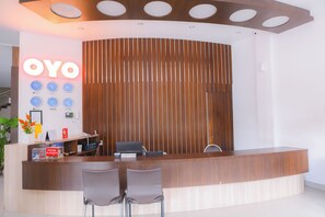 A reception desk with a wooden finish, a clock display, and a nameplate for the receptionist.
