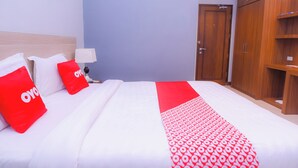 Une chambre d’hôtel avec un lit bien fait, une table de chevet avec une lampe et une armoire.
