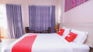 Une chambre d’hôtel avec un grand lit, une tête de lit en bois, une petite table et deux chaises.
