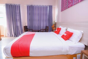 Ein Hotelzimmer mit einem großen Bett, einem Holzkopfende, einem kleinen Tisch und zwei Stühlen.