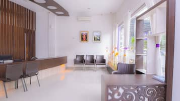 A reception area with a wooden reception desk, several chairs, and a decorative wall panel.