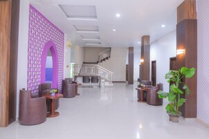 A modern lobby with a staircase, seating area, and a reception desk.