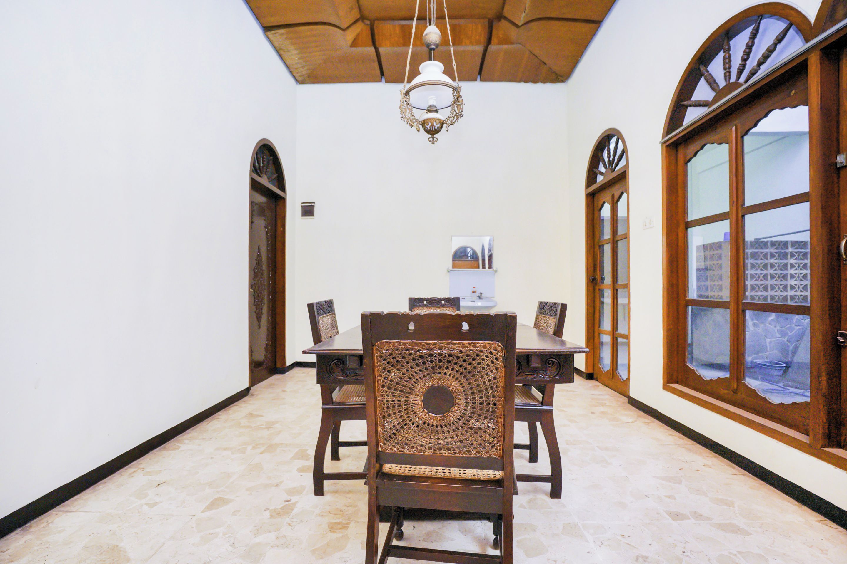 A dining area with a table and chairs, a chandelier, and a view through a large window.