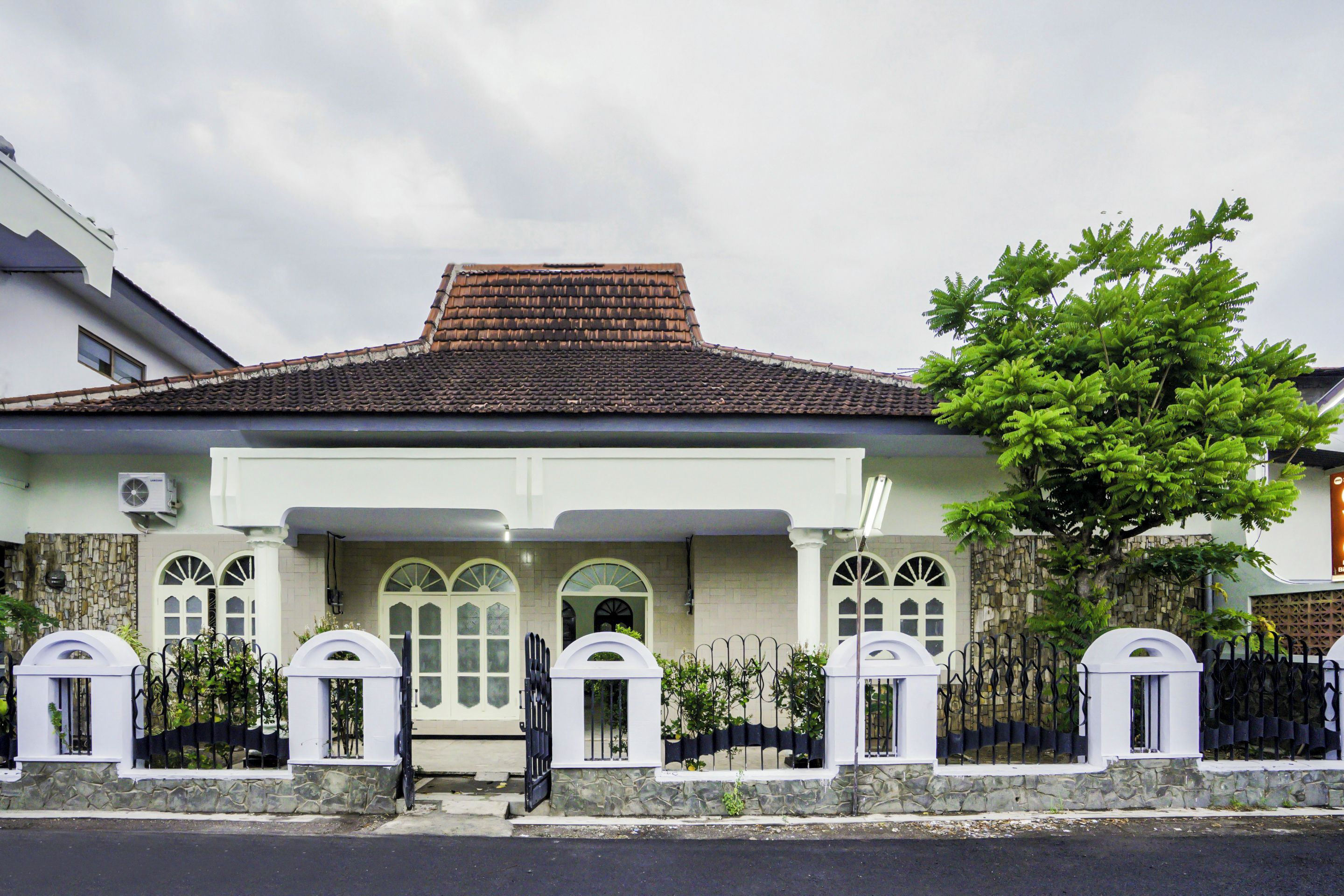 A two-story house with a tiled roof, stone walls, and a gated entrance.