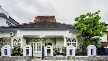 A two-story house with a tiled roof, stone walls, and a gated entrance.