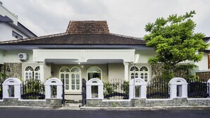 A two-story house with a tiled roof, white walls, and a stone foundation. - Oyo 2004 Penginapan Bidara Syariah (Probolinggo)