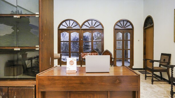 A wooden reception desk with a laptop, a sign, and a chair. - Oyo 2004 Penginapan Bidara Syariah (Probolinggo)