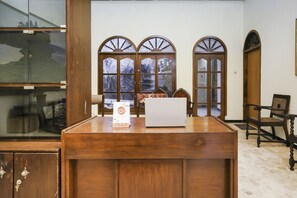 A wooden reception desk with a laptop, a sign, and a chair. - Oyo 2004 Penginapan Bidara Syariah (Probolinggo)