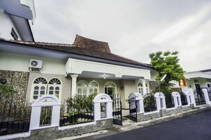 A two-story house with a stone facade, white trim, and a tiled roof.