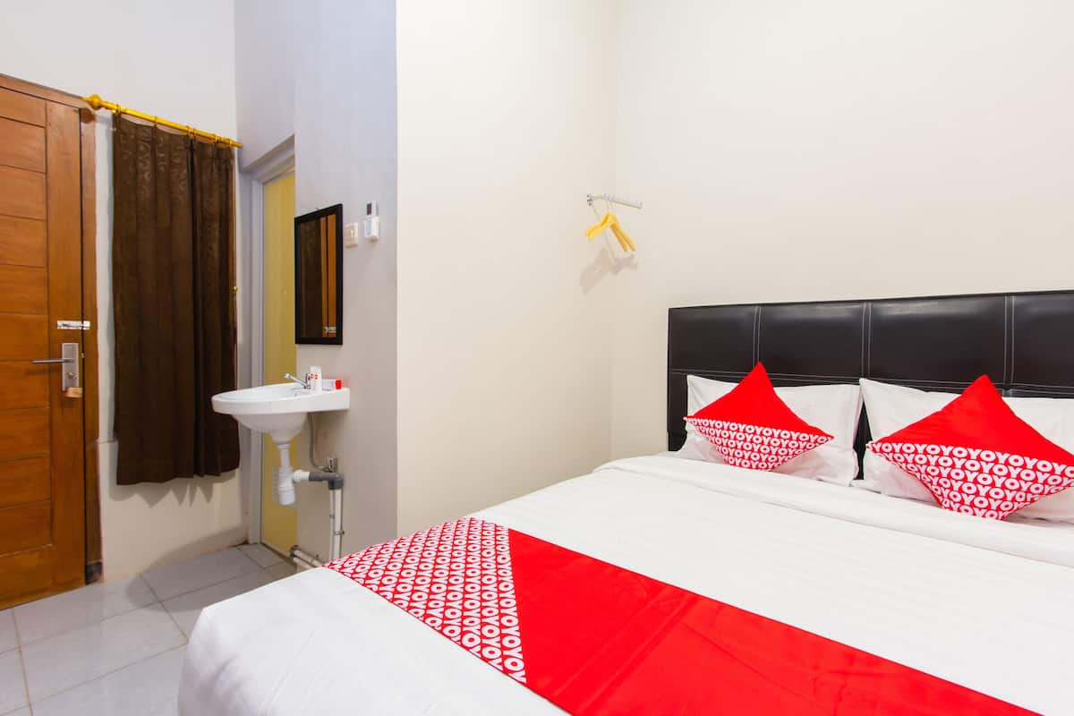 A hotel room with a bed, a bathroom, and a door.