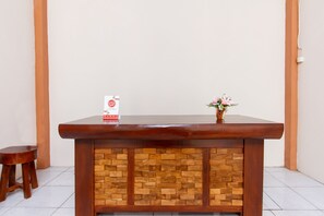 Un comptoir d’accueil avec un revêtement en bois et une partie inférieure décorée d’un motif imitant des briques. Un petit vase avec des fleurs est posé sur le comptoir.