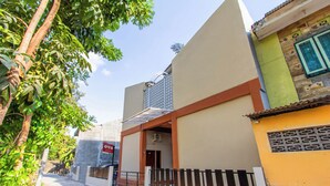 Un edificio residencial con acceso por portón, unidad de aire acondicionado visible y un cartel.