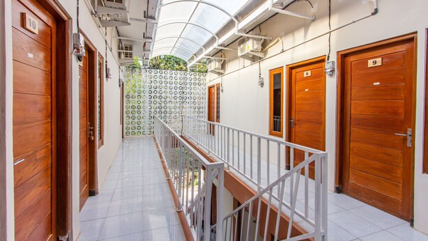 A corridor with wooden doors numbered 8, 9, and 10, leading to rooms. - Oyo 1718 Homestay Wak Gobenk (Depok)