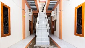 Una escalera en un pasillo con paredes blancas y detalles de madera.