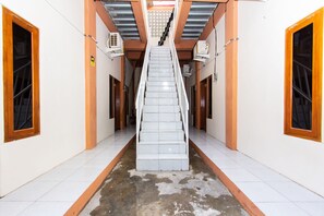 Un escalier dans un couloir aux murs blancs et aux éléments décoratifs en bois.